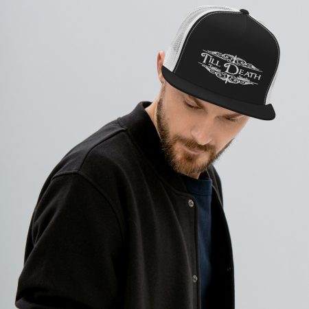 A man wearing a black jacket and a "5-Panel Trucker Cap" looks down against a plain background, embodying the rugged style you'd expect to find in a tattoo studio.