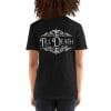 A person is wearing a black unisex basic softstyle T-shirt, which has "Till Death Tattoo Studio" printed in white decorative text on the back.