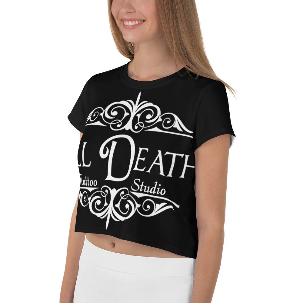 A woman elegantly models an all-over-print crop tee with white decorative elements, standing against a plain background.