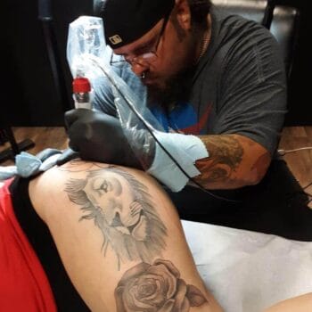 At Till Death Tattoo Studio, the skilled artist known by the product name Brandon-Williams2-1, expertly crafts an intricate lion and rose design on a client's arm near Auburndale, showcasing remarkable artistry and precision.